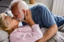Pareja mayor besándose en la cama